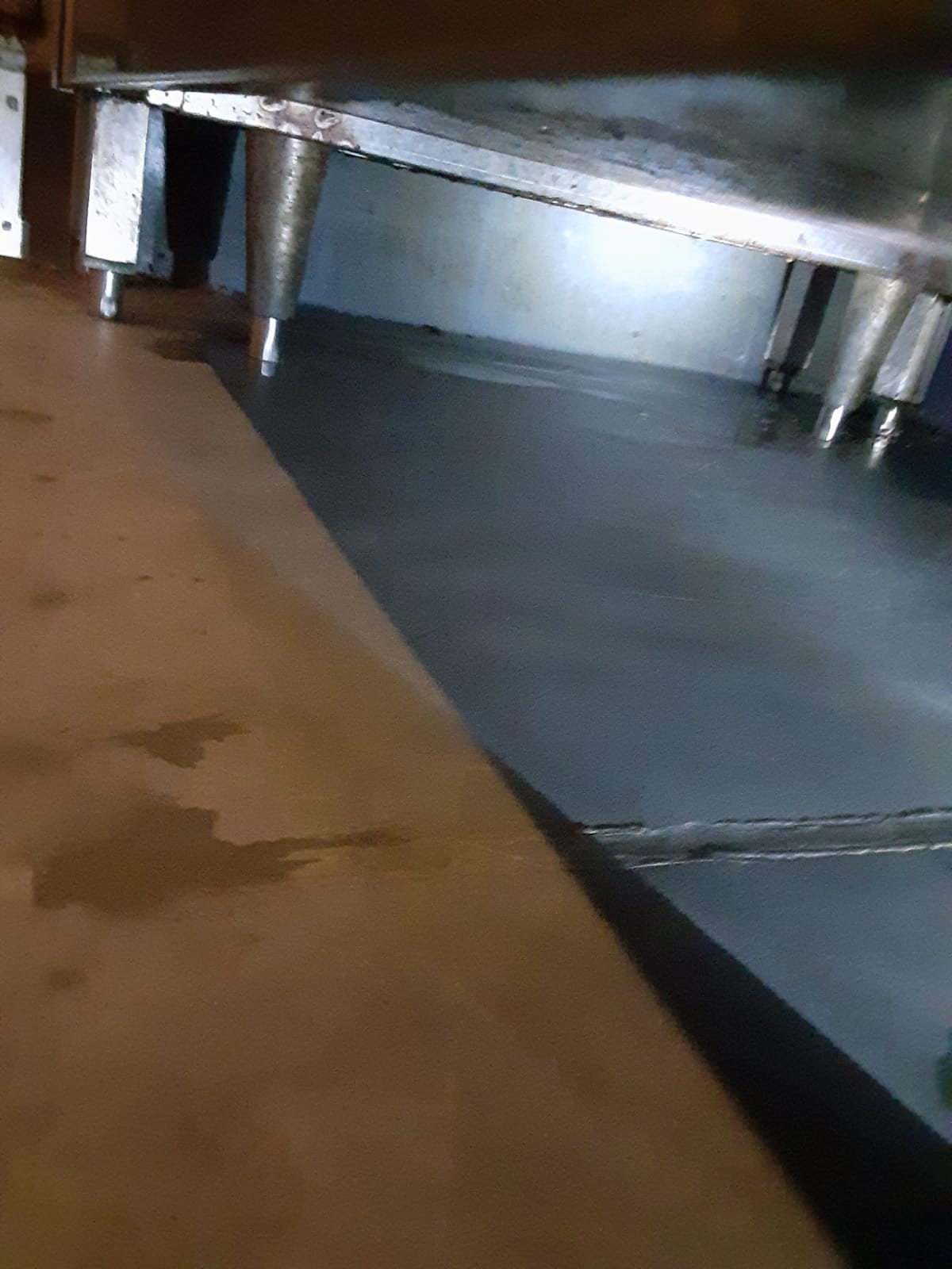 Close documentation photo of a kitchen floor and equipment legs, the kind of detail a restaurant cleaning checklist has to cover
