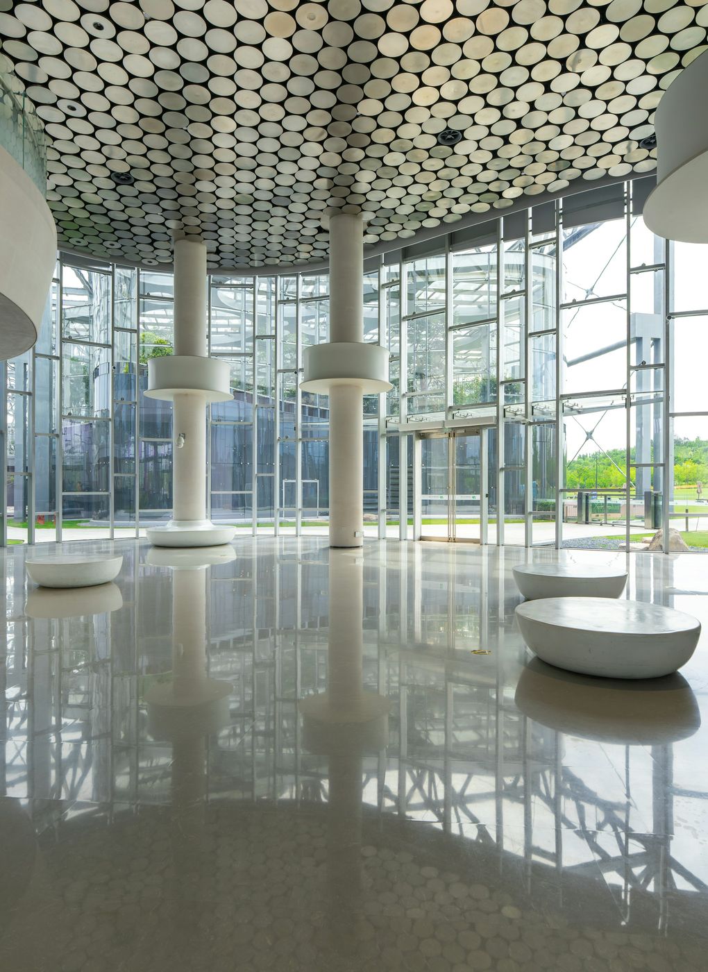 A glass atrium with a polished floor reflecting the columns