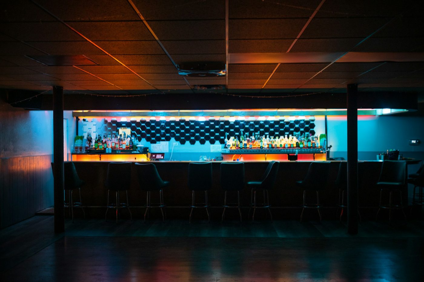 A bar after close, lit only by its back bar