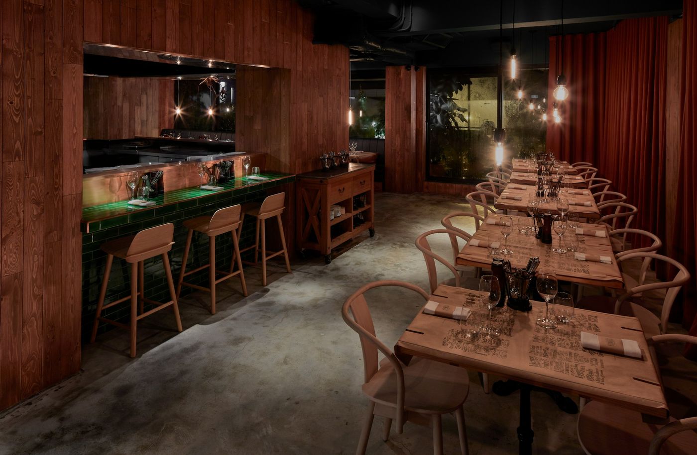 A restaurant dining room and bar set for service, with the open kitchen behind