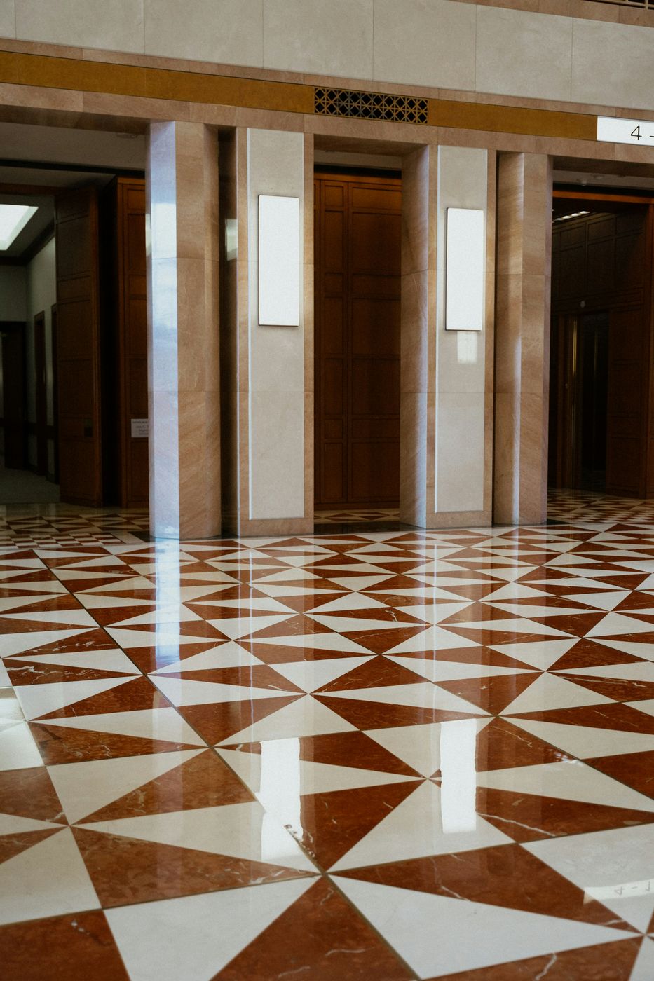 An elevator lobby with a polished red and white marble floor