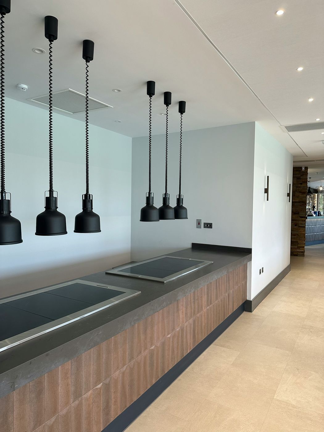 A hotel kitchen with heat lamps over clean counters and a tiled floor