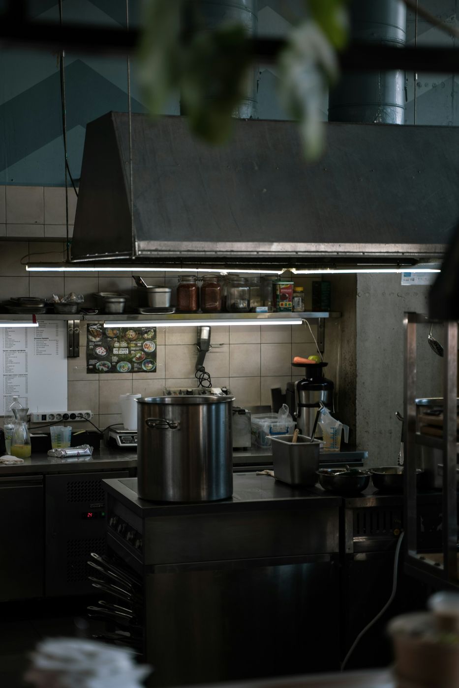 A commercial kitchen with a stainless hood over the range and a stockpot on the line
