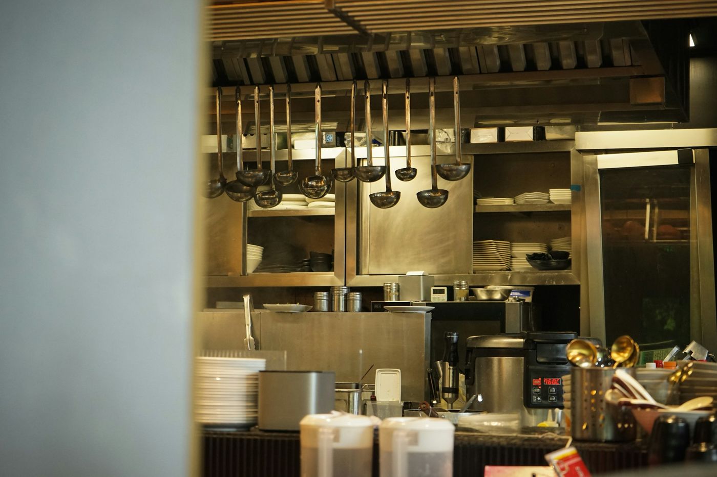 Ladles hanging over a stainless pass with stacked plates