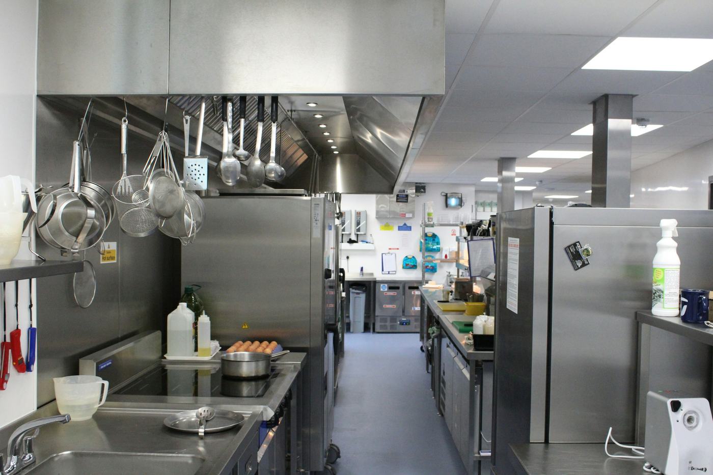 A commercial prep kitchen aisle with stainless worktops