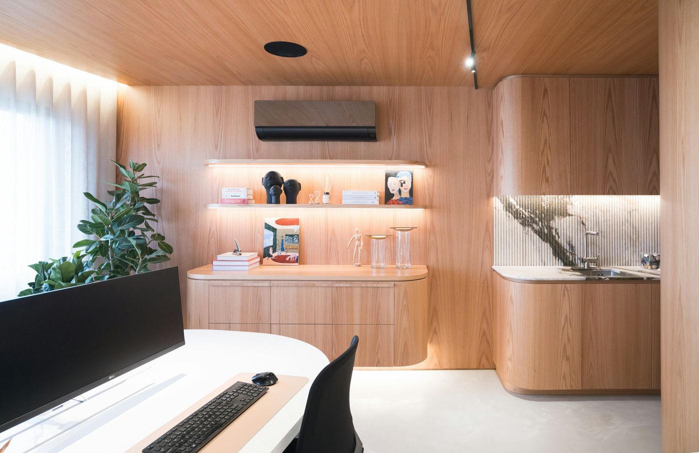 An office kitchenette with wood cabinets and a stone backsplash