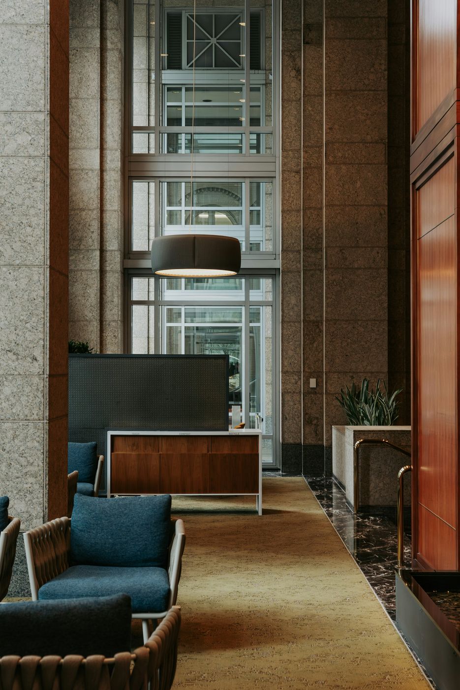 An office lobby with lounge chairs, a reception desk and a polished floor