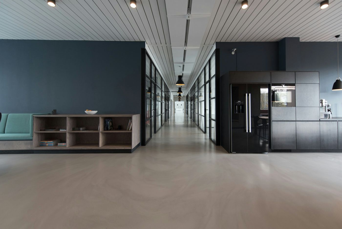 An office corridor with glass walls and a smooth grey floor