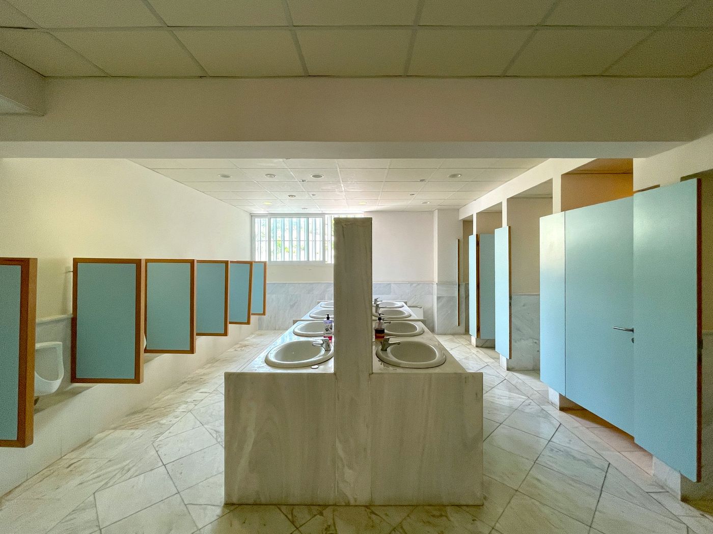 An office restroom with stone sinks and pale blue stall doors
