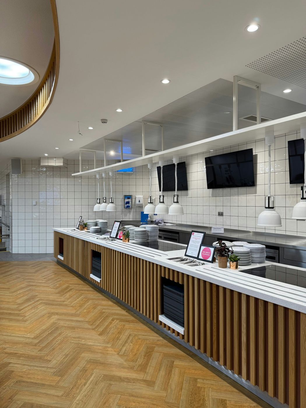 A new serving counter with white heat lamps, stacked plates and a wood-slat front