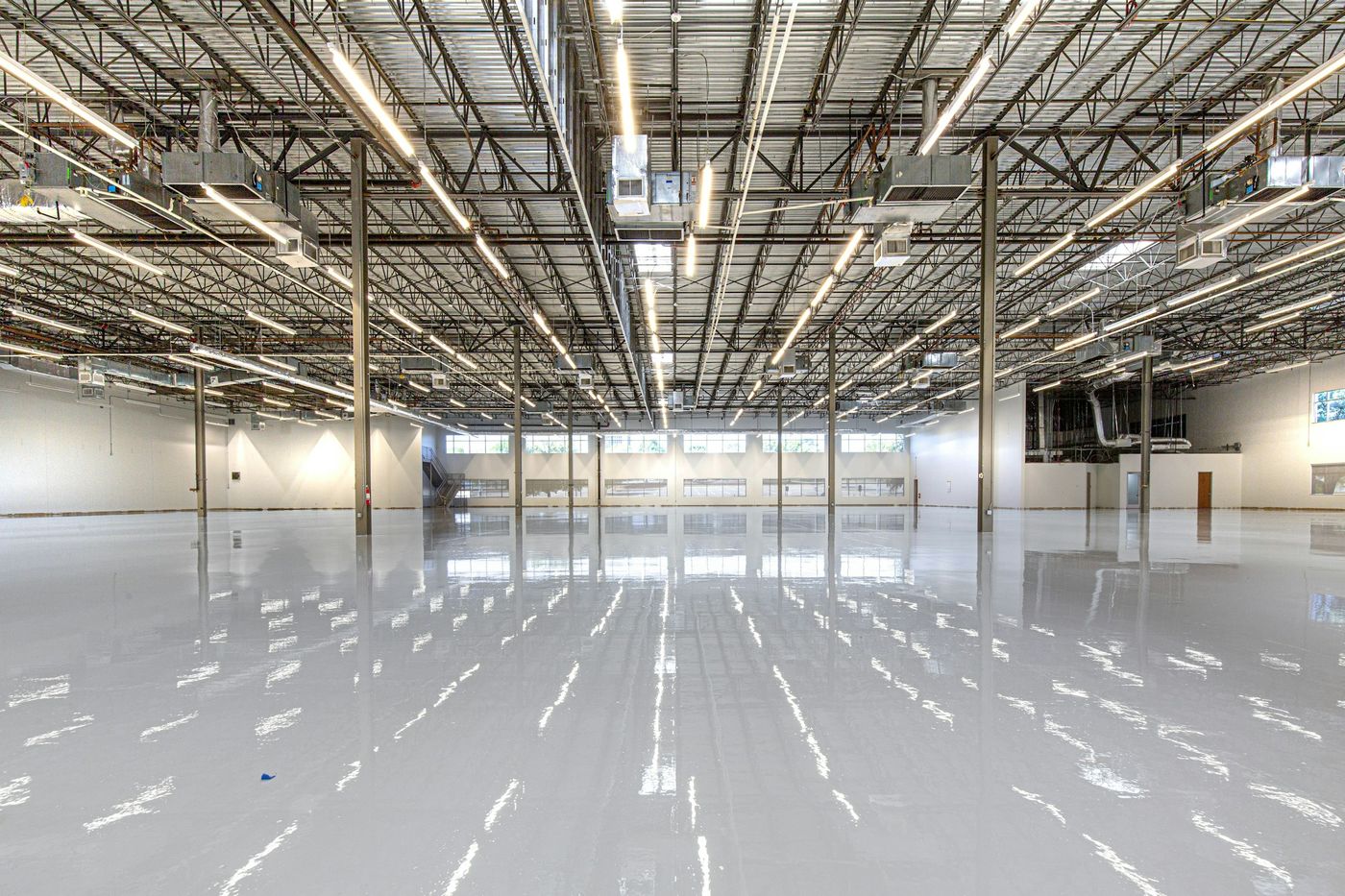 A large new building with a freshly coated grey floor reflecting rows of lights